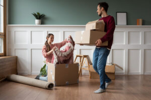 A man and a woman unpack boxes in a living room